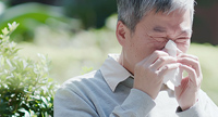 A man sneezing due to seasonal allergies.