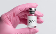 Hand in a pink glove hold ing a GLP-1 vial