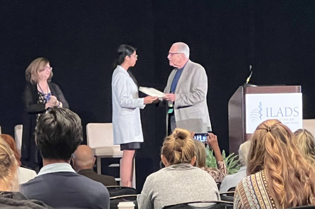 Dr. Leo J. Shea III, PhD (right), former two-term president of ILADS, presenting Kayla M. Socarras (left), PhD Candidate, Department of Microbiology and Immunology, with the 2022 ILADS Neil Spector Humanitarian Award.